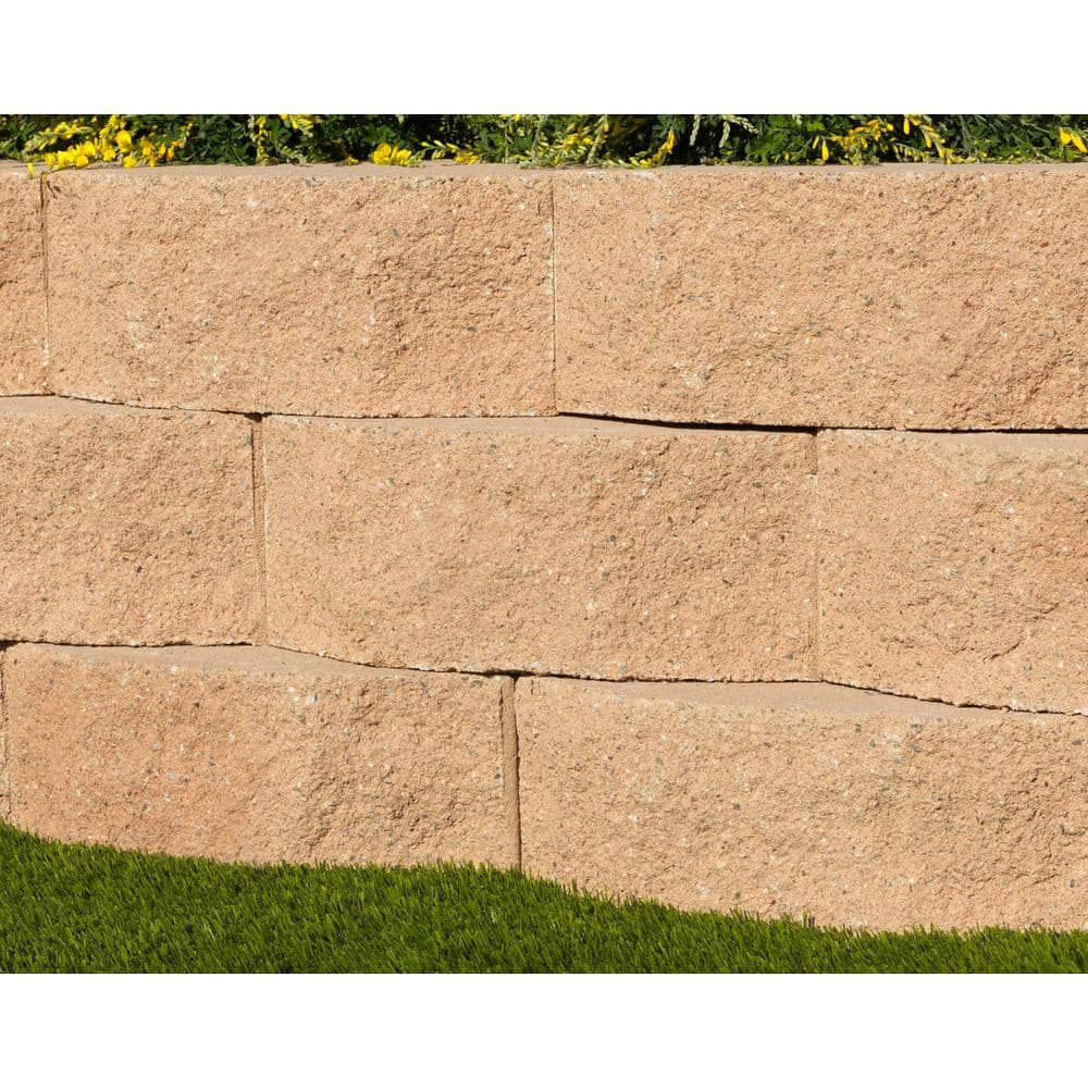 Tan concrete garden wall blocks dry-stacked into a low retaining wall on a landscaped slope
