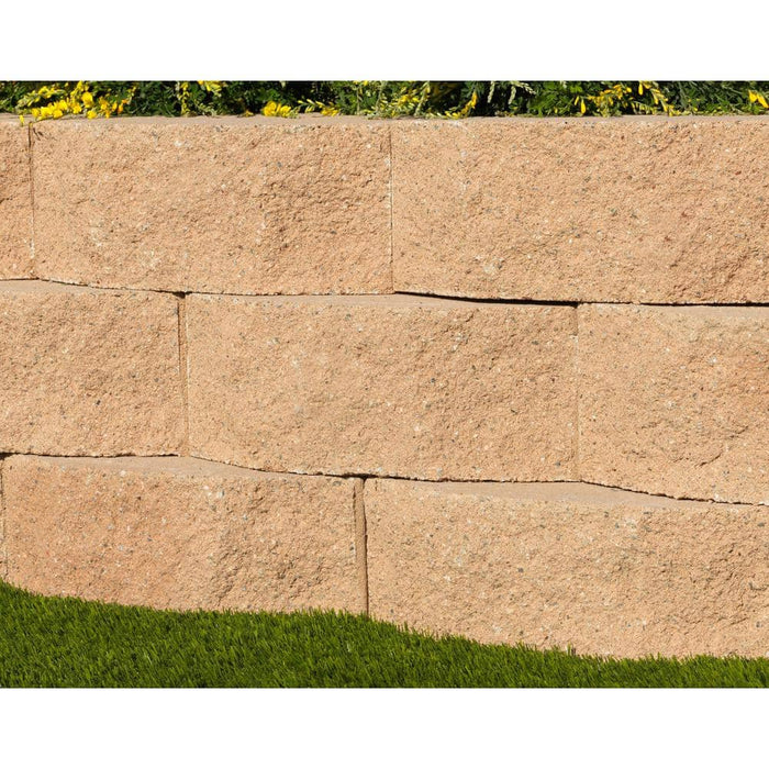 Tan concrete garden wall blocks dry-stacked into a low retaining wall on a landscaped slope