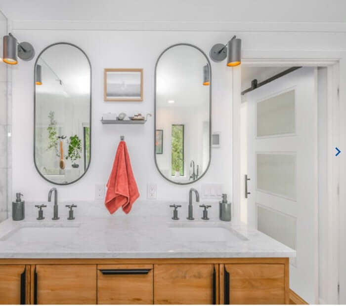 Modern bathroom with double mirrors, sleek faucet fixtures, and a stylish wooden vanity.