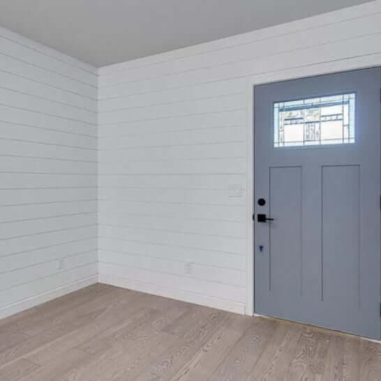 Interior view showcasing MDF Shiplap 5/8 in. x 6 in. x 16 ft. Primed 2010LDF on walls with a blue door.