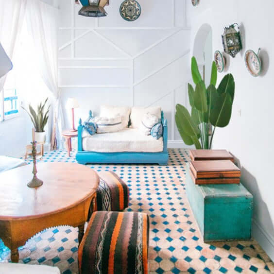 Stylish living room featuring a blue couch, wooden table, and decorative plants with colorful patterned flooring.