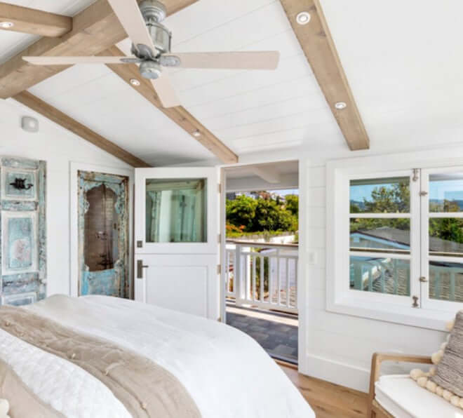 Bright interior of a bedroom featuring a ceiling fan, natural light, and a welcoming view through open doors and windows.