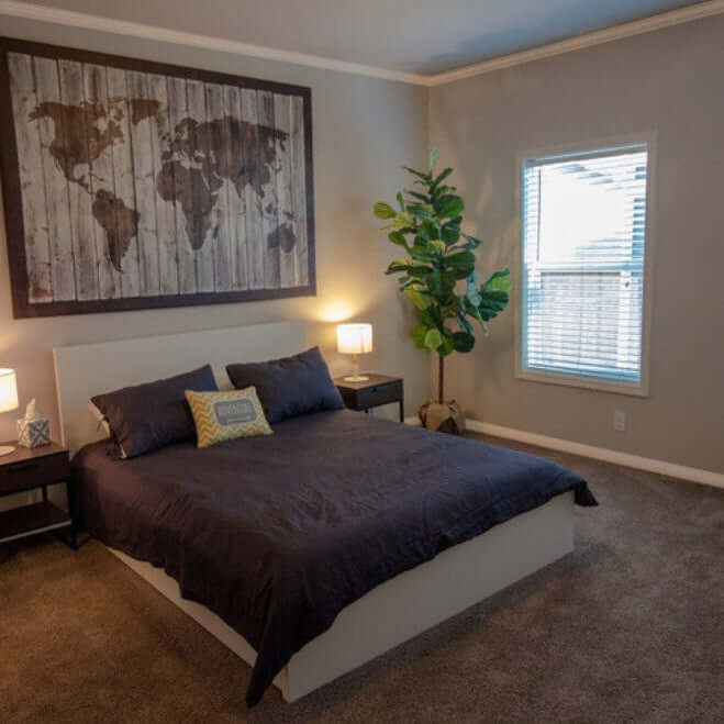 Cozy bedroom with a contemporary bed, world map artwork, and indoor plant in a well-lit space.