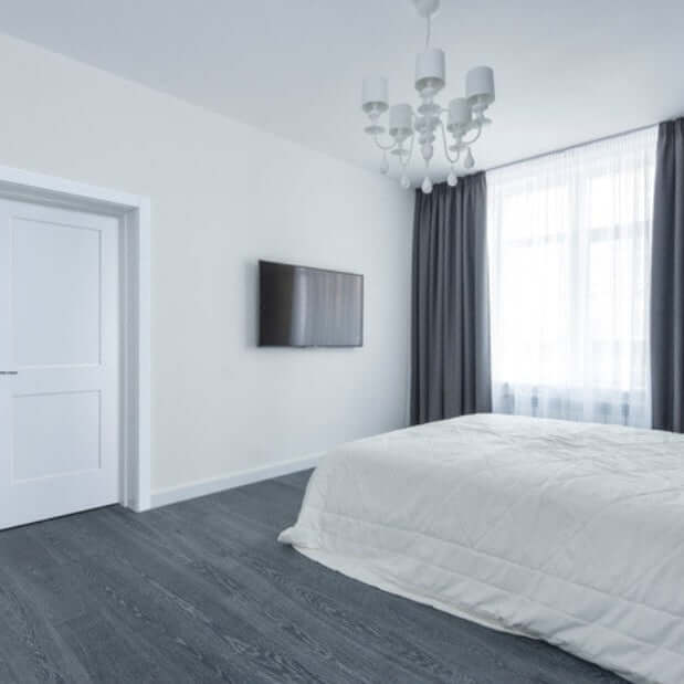 Modern bedroom design featuring a white bed and gray curtains, with a TV mounted on the wall.