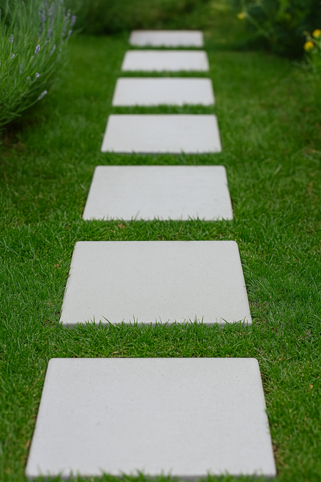 Outdoor path made from square white concrete pavers surrounded by flowers and plants
