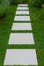 Outdoor path made from square white concrete pavers surrounded by flowers and plants